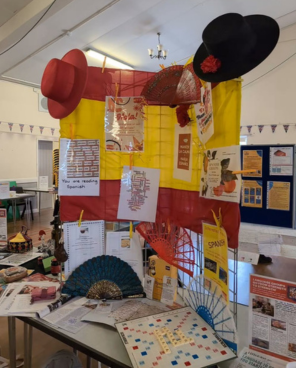 A table display with a Spanish flag, hats and posters
